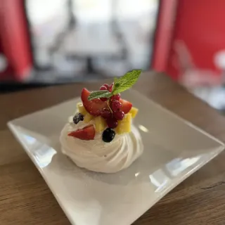 Pavlova maison garnie de chantilly, fraises, groseilles et ananas